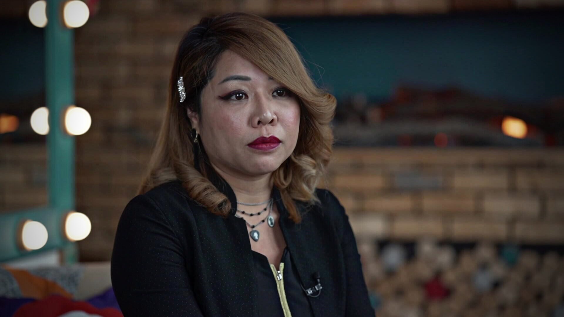 中国女人，棕色头发，穿黑色夹克。