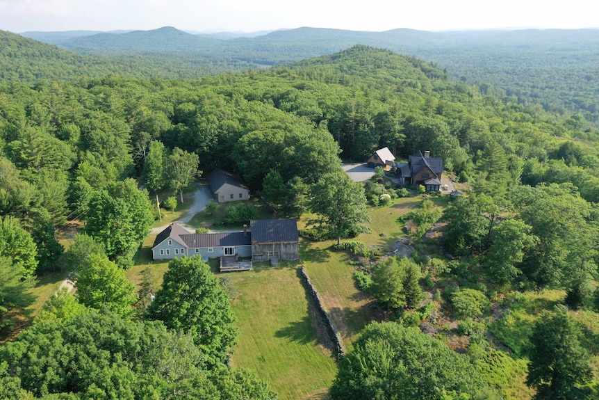 An aerial image of a house nestled among forested hills.