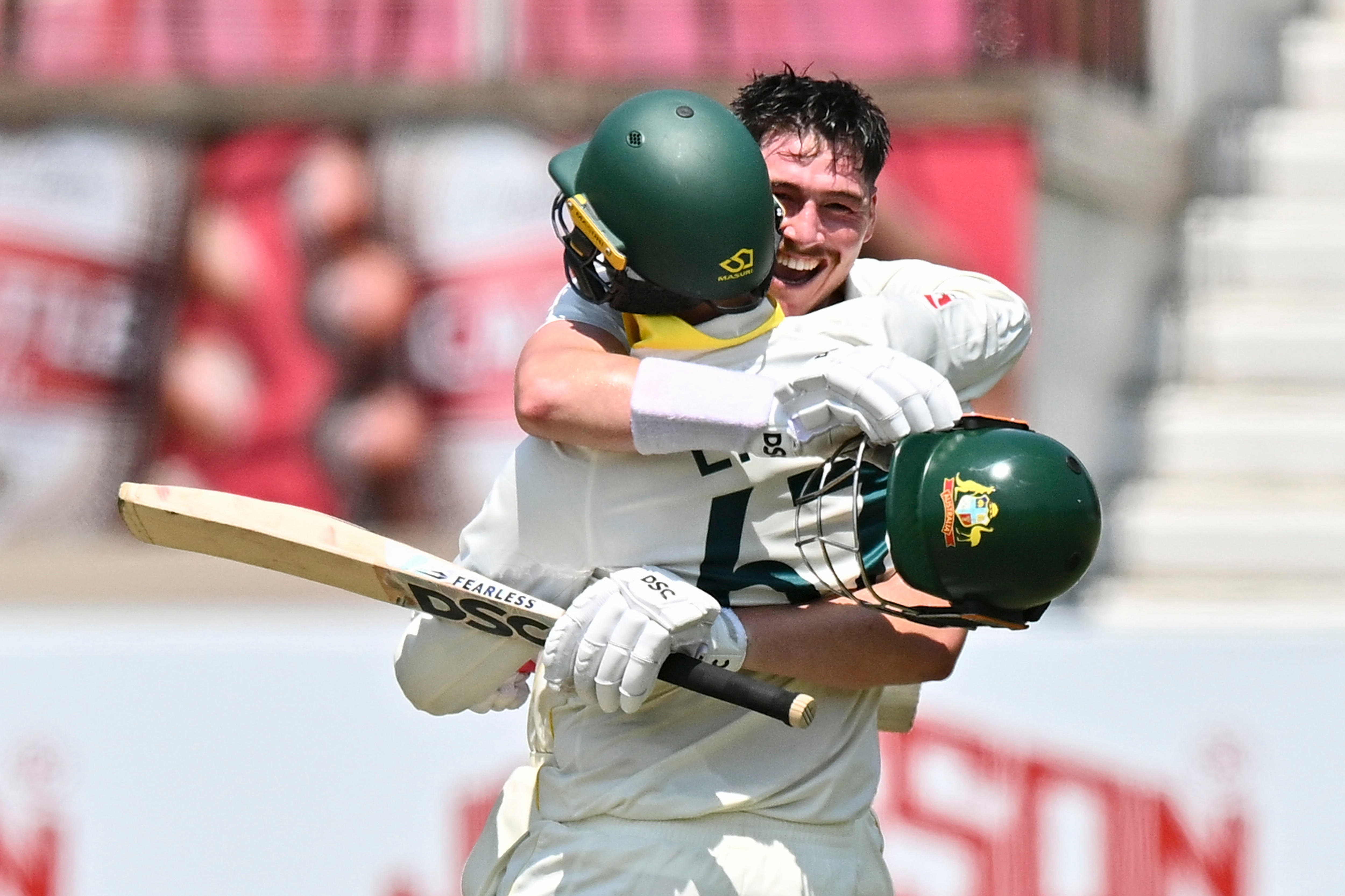 Matthew Renshaw hugs Nathan Lyon after reaching 100 in a cricket Test against South Africa.