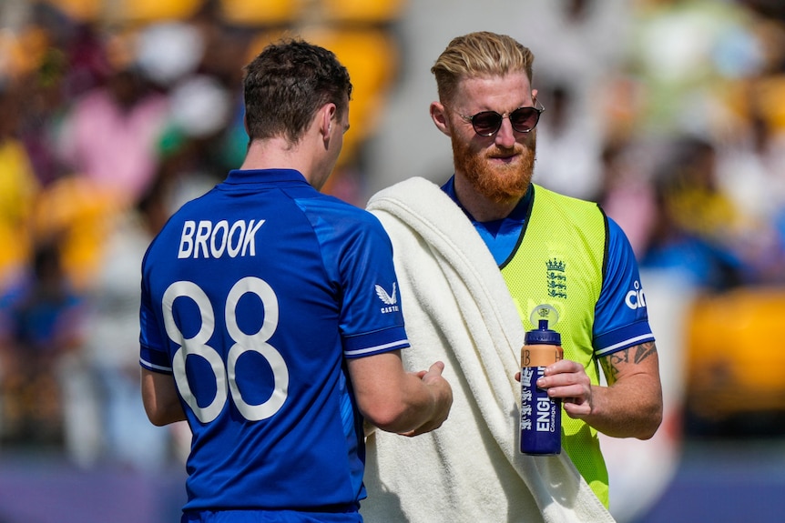 Ben Stokes gives a drink to Harry Brook during England's Cricket World Cup match against Bangladesh.