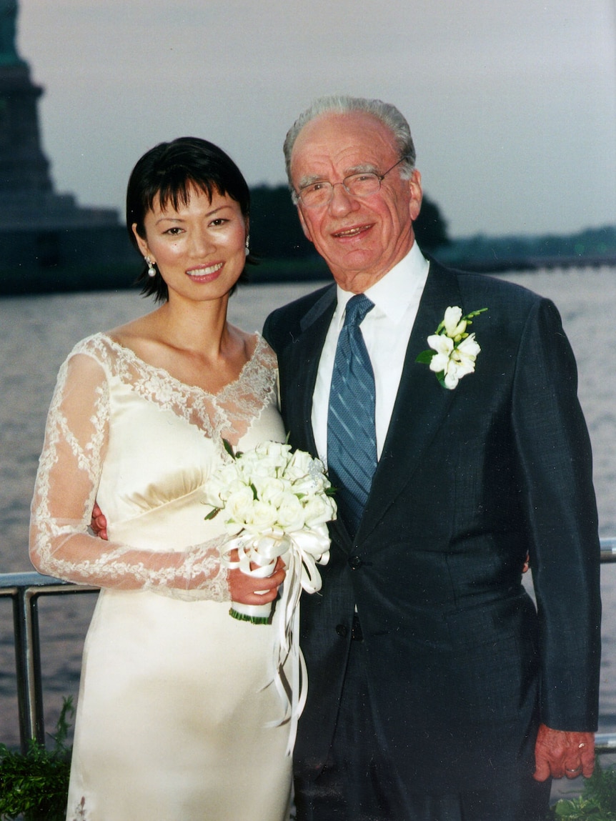 Wendi Deng in a white lace wedding dress, holding a bouquet, next to Rupert Murdoch in a suit