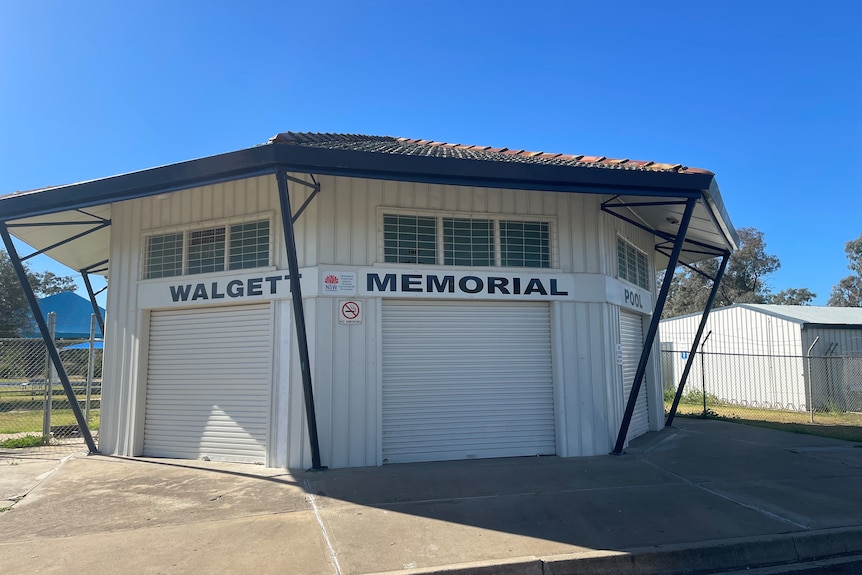 Three white shutter roller doors are closed at a building that says Walgett Memorial Pool