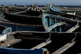 A closely framed picture of several wooden boats sitting in a harbour