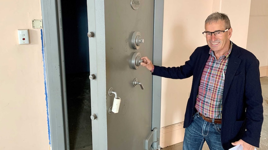 A man stands next to a 90 year old Chubb safe he discovered while renovating a bank building