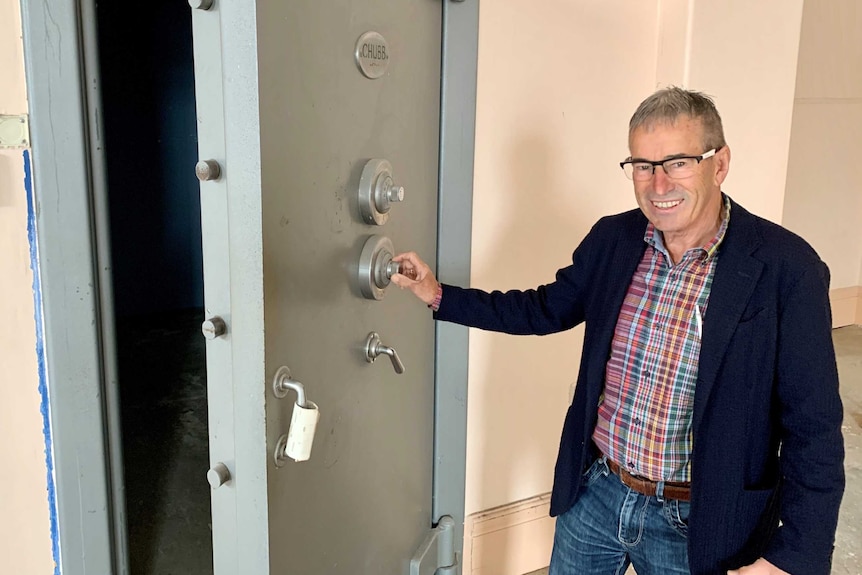 Kevin Coote stands next to the 90 year old Chubb safe he discovered while renovating the bank