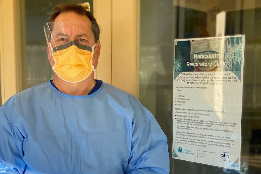 Man with mask holding vaccine outside a clinic