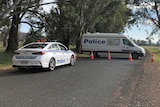 police wagon and car blocking a rural road