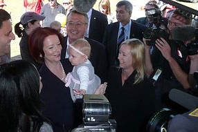 Julia Gillard holds a baby in Brisbane on day one of the 2010 election campaign (ABC)