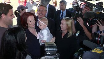 Julia Gillard holds a baby in Brisbane on day one of the 2010 election campaign (ABC)