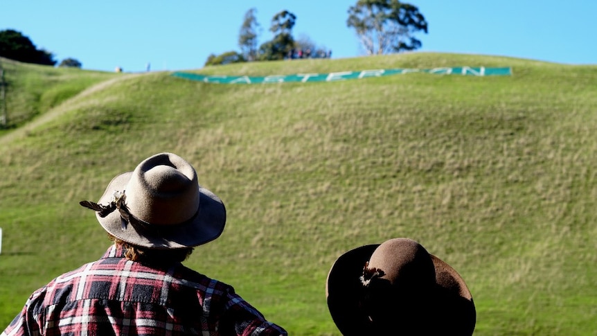 Two spectators look up at the hill and its Casterton sign during the hill climb event