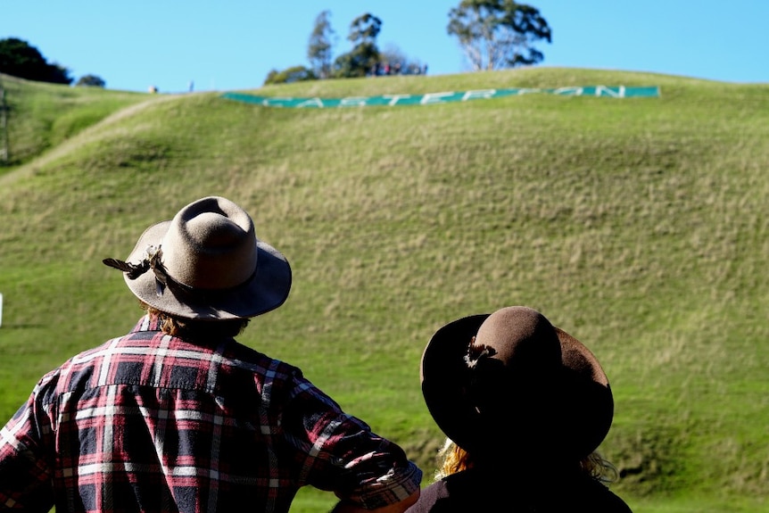 Two spectators look up at the hill and its Casterton sign during the hill climb event