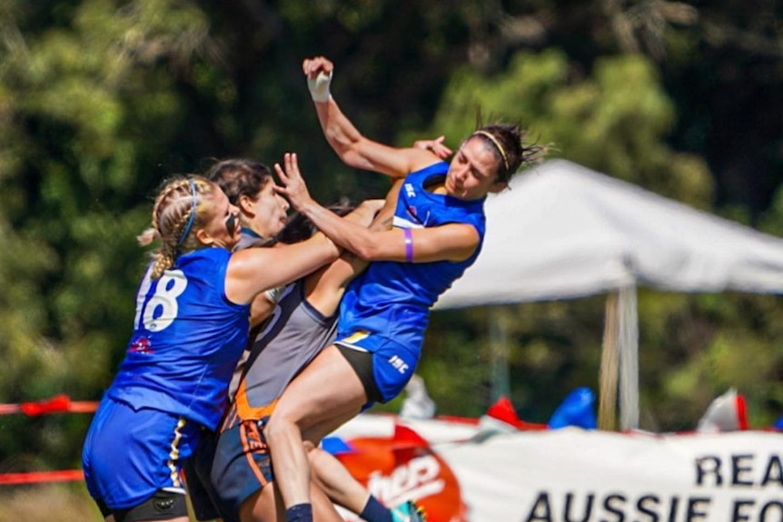 Four women jump for a mark in a game of Australian Football. 