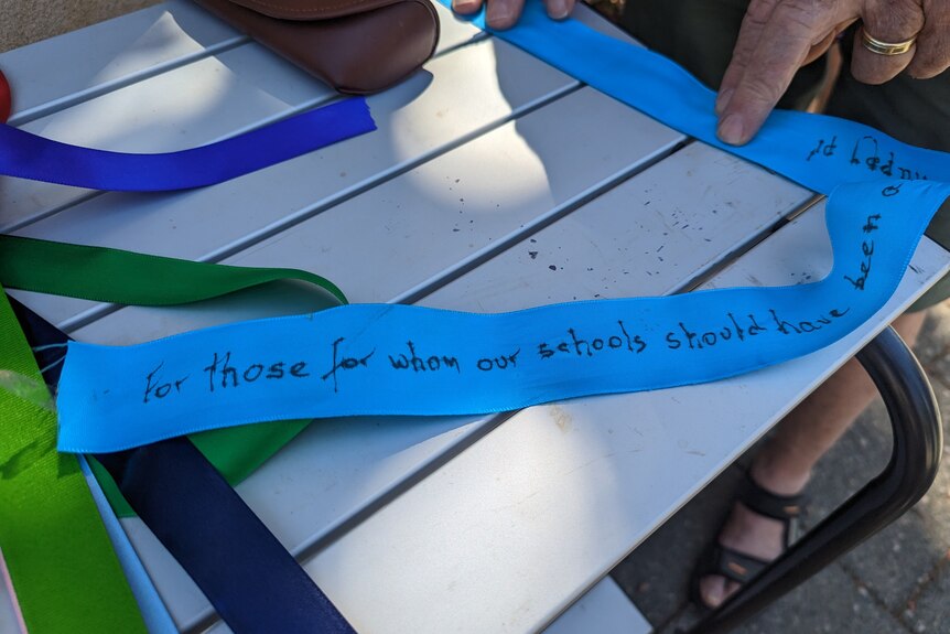 A blue ribbon with a message that starts "for those for whom our schools should have been ... "