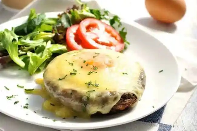 A plate with mushroom and baked eggs covered in melted cheese