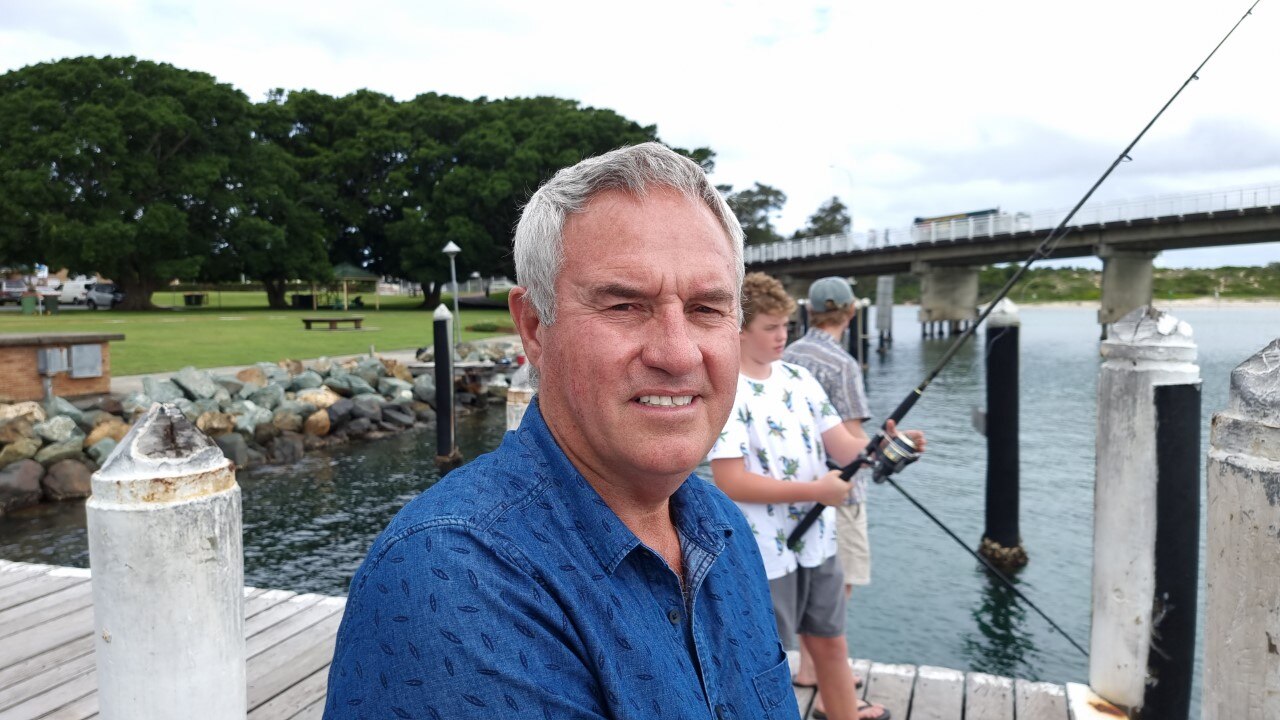 Tony Lorendo on a pier wearing a blue shirt, as children use fishing rods behind him.