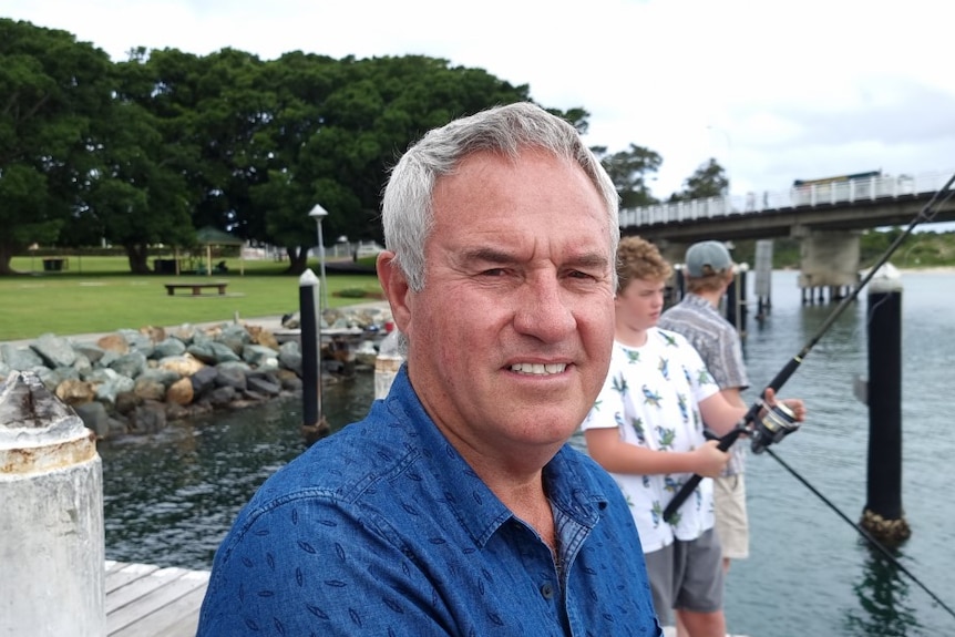 Tony Lorendo on a pier wearing a blue shirt, as children use fishing rods behind him.