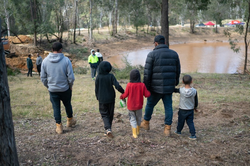 A man with children near a dam on a rural property.