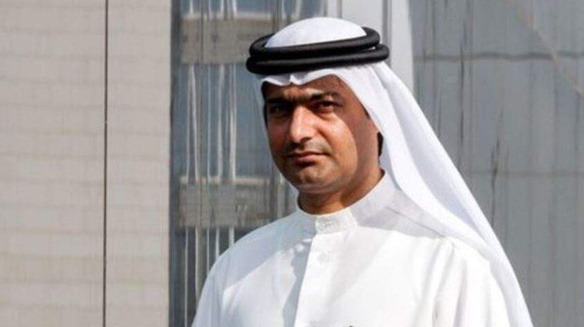 Ahmed Mansoor stands beside his reflection in a mirrored wall, wearing traditional white garb.