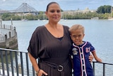 A woman and her son standing at a railing that overlooks the Brisbane River, the Story Bridge behind them