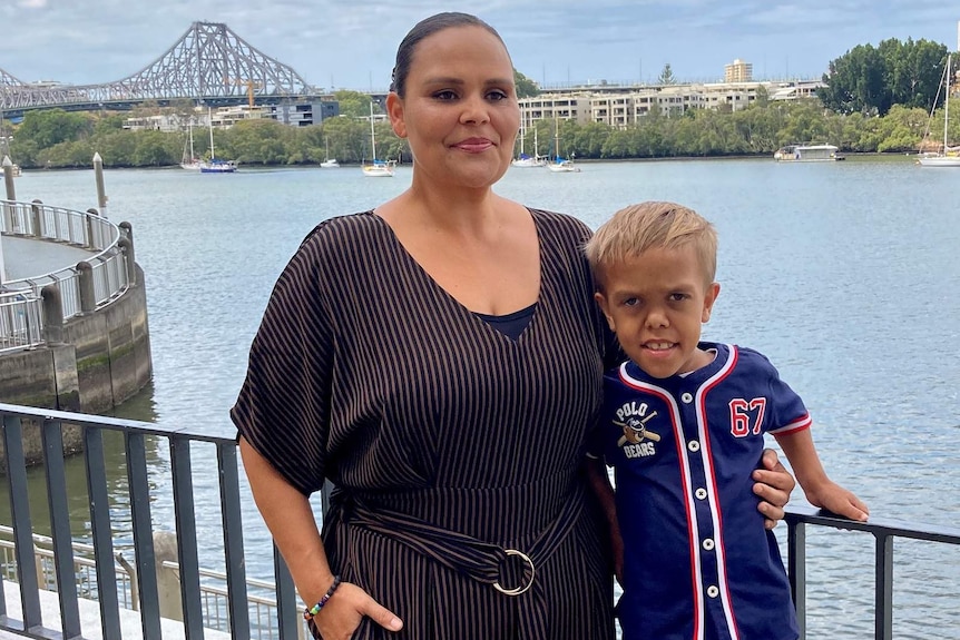 A woman and her son standing at a railing that overlooks the Brisbane River, the Story Bridge behind them