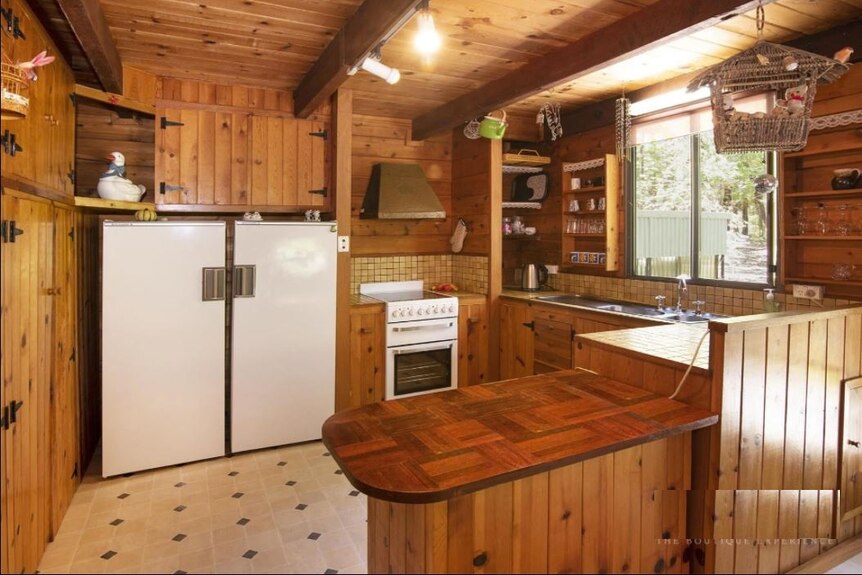A smallish kitchen space with a wooden bench and tiled floor.