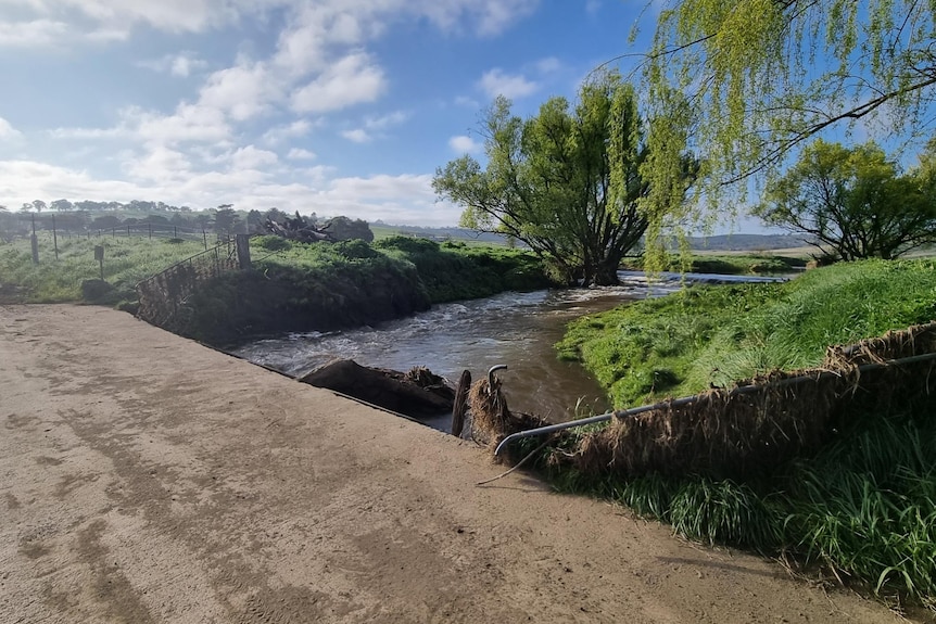 A cement crossing over a river with a dirt road on either side.