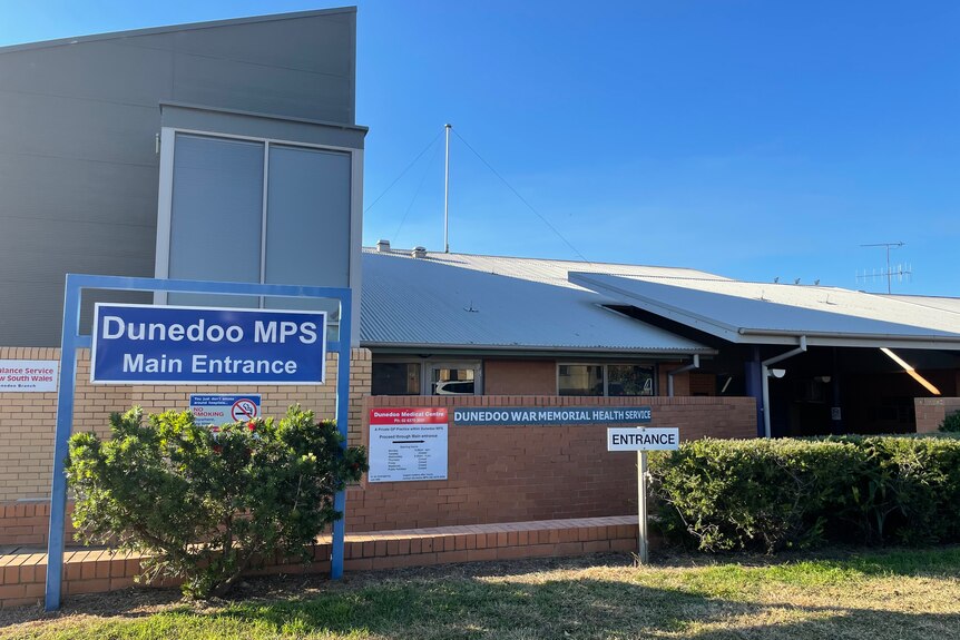 Exterior of the Dunedoo hospital building, featuring some lawn and a blue sign reading 'Dunedoo MPS main entrance'