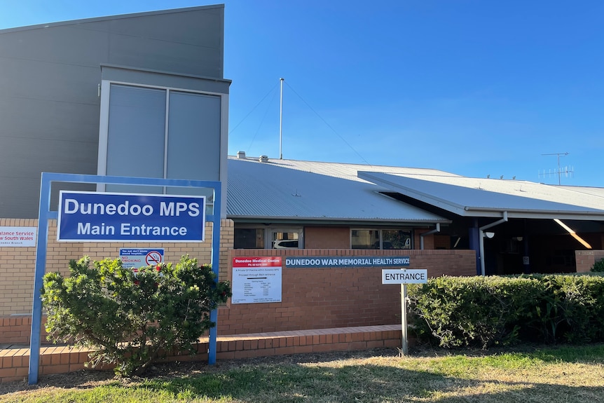 Exterior of the Dunedoo hospital building, featuring some lawn and a blue sign reading 'Dunedoo MPS main entrance'