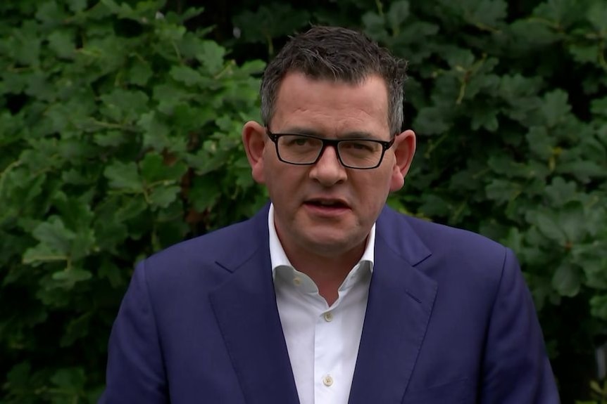 Daniel Andrews in front of a hedge