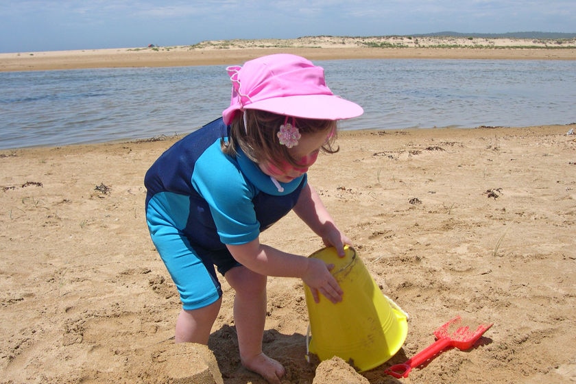 Young girl building sand castle on a beach