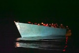 A low boat full of people, at night.