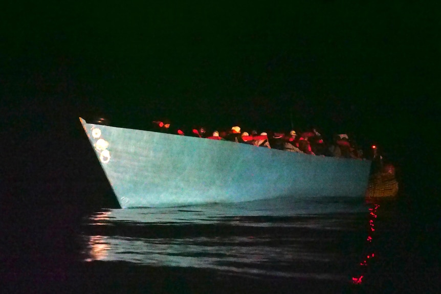 A low boat full of people, at night.