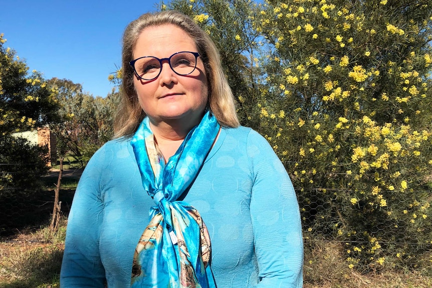 Jane Quinn wears a blue top and blue scarf.