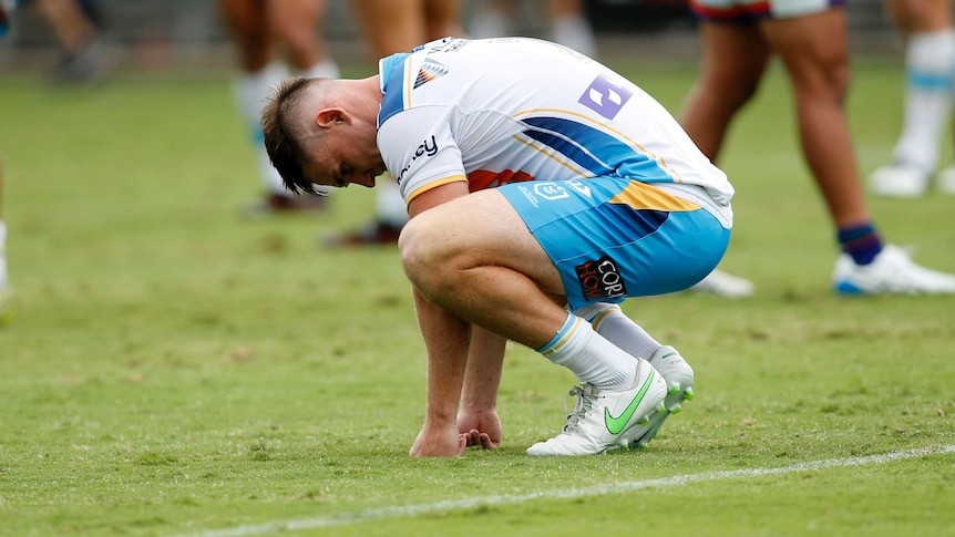 Gold Coast Titans player AJ Brimson squats on the ground after an NRL match.