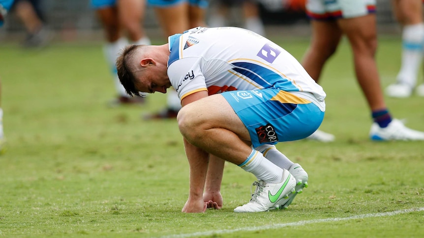 Gold Coast Titans player AJ Brimson squats on the ground after an NRL match.