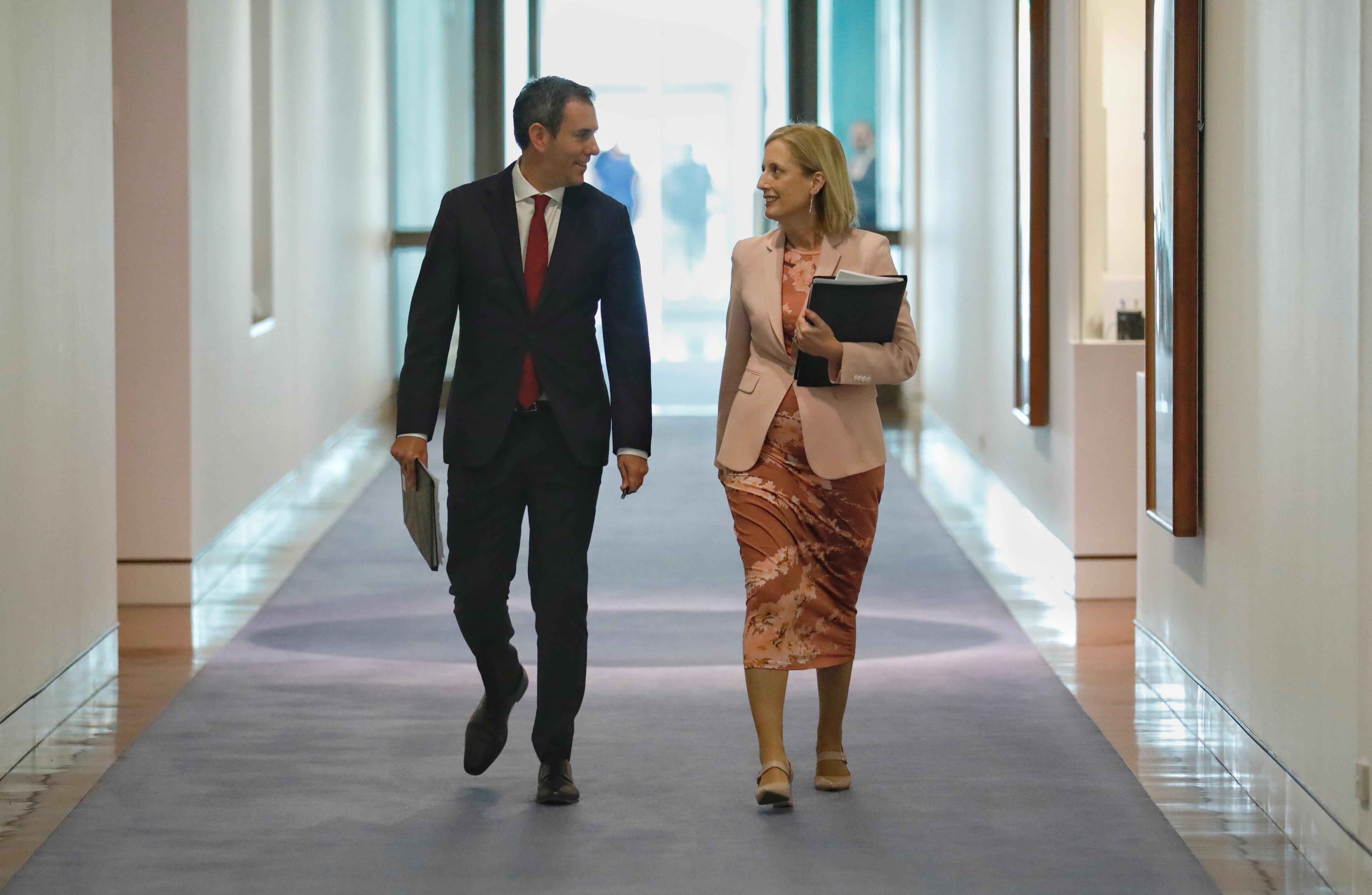Jim Chalmers and Katy Gallagher talk while walking in a parliament house corridor 