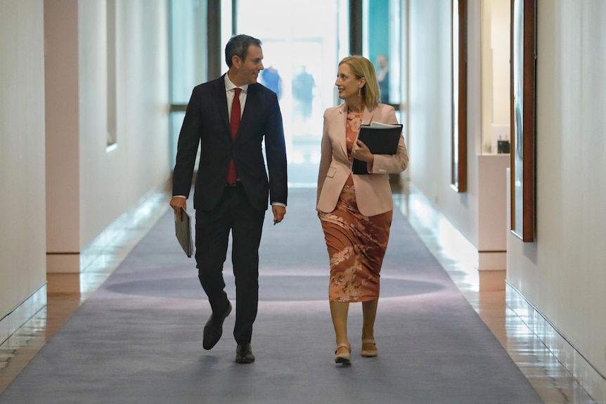 Jim Chalmers and Katy Gallagher talk while walking in a parliament house corridor 