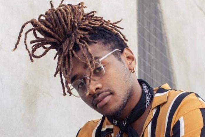 JJay De Melo sits on a staircase, looking at the camera