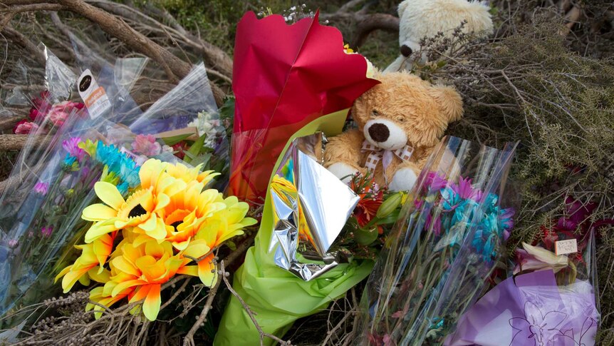Flowers and a teddy bear by the road