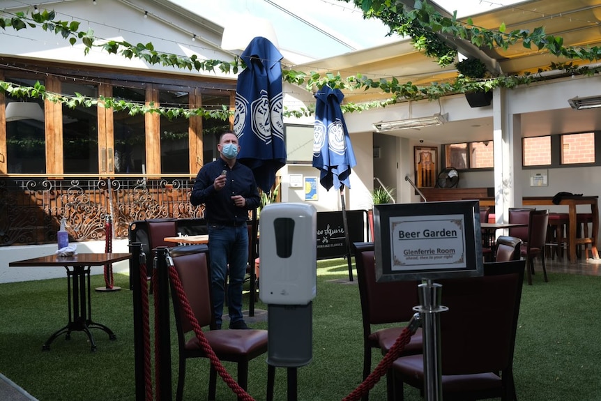 A man standing in a pub courtyard with a QR monitor in the foreground.