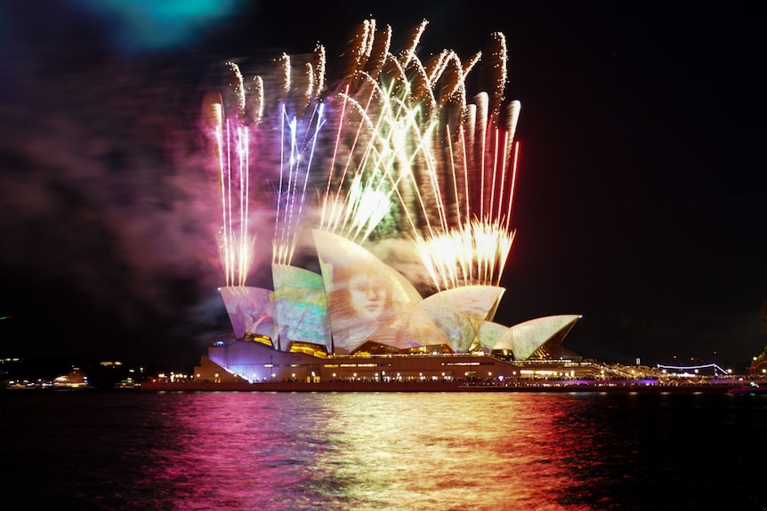 fireworks over the opera house sails lit up with images for the opening of vivid 2024