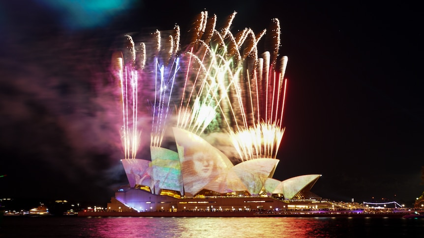 fireworks over the opera house sails lit up with images for the opening of vivid 2024