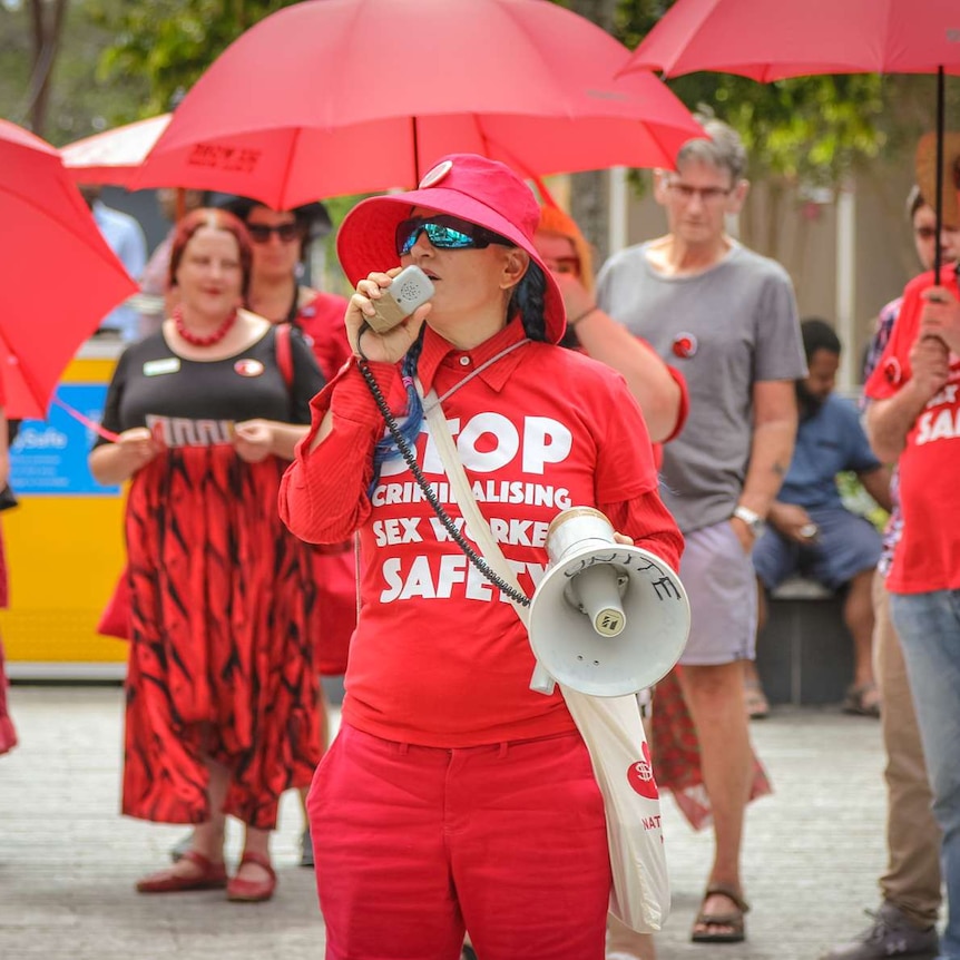 A woman with a red shirt and loudspeaker addresses a rally.