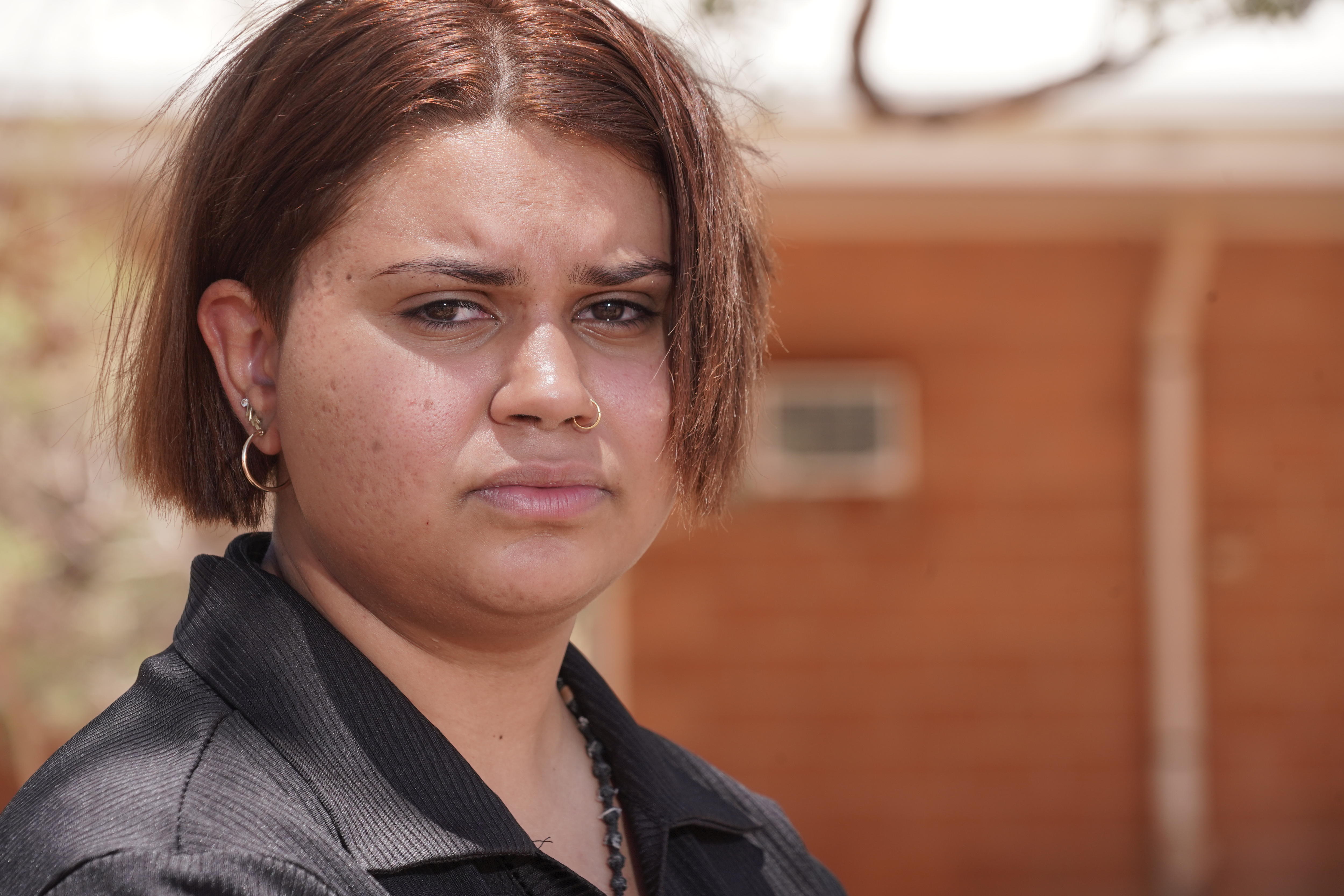A young woman standing outside a building and looking serious.