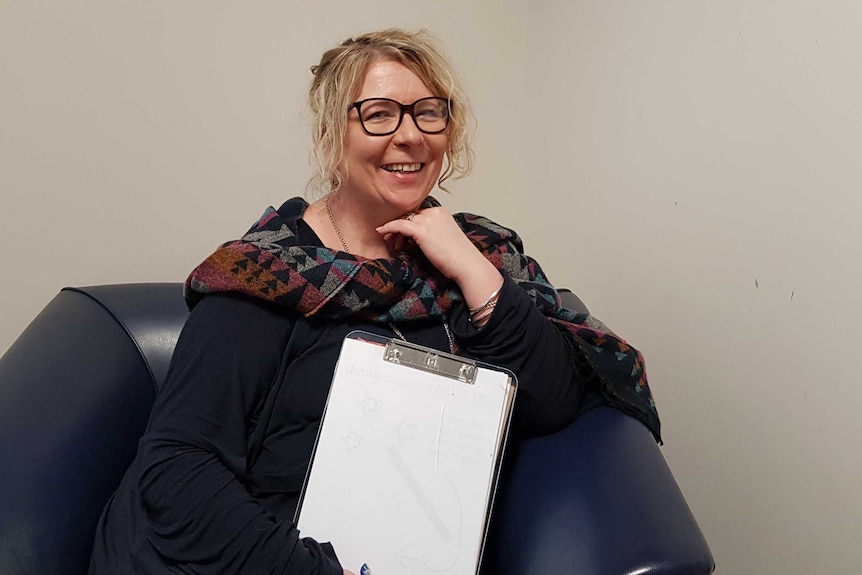 Jo White sits with a clipboard in her counselling office.