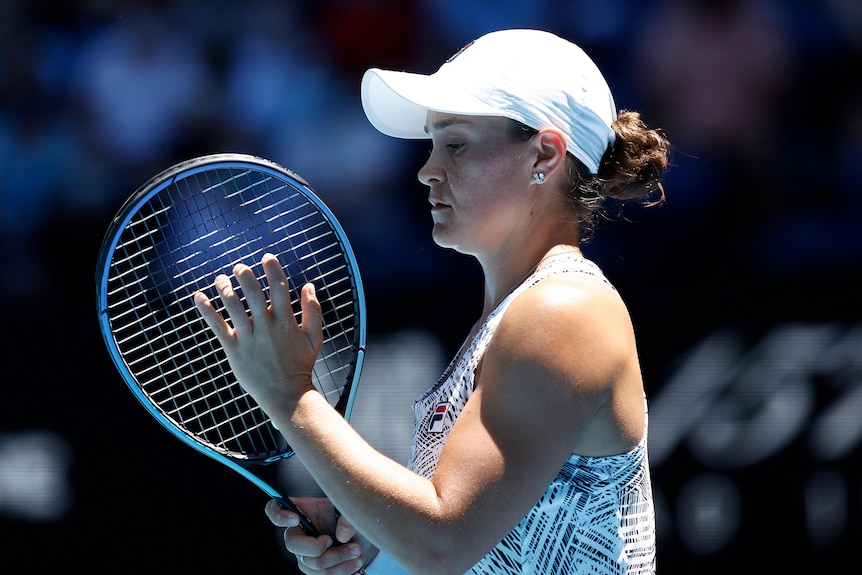 A female Australian tennis player checks the strings on her racquet at the Australian Open.