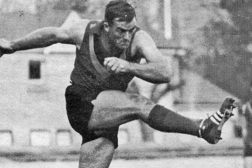 A black and white photo of a footballer kicking a ball