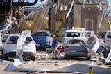A man looks at a damaged car after a tornado hit the day before