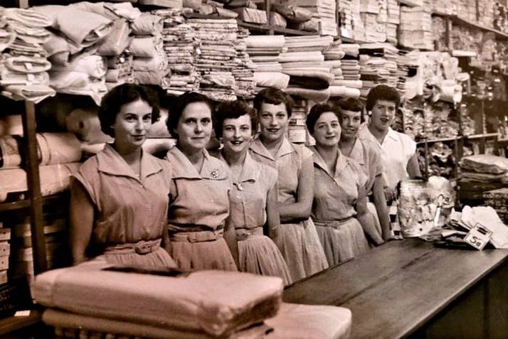 A black-and-white photograph showing women in a materials store in the 1950s.