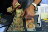 A cashier changes a 50 Euro banknote with US dollars at an exchange counter